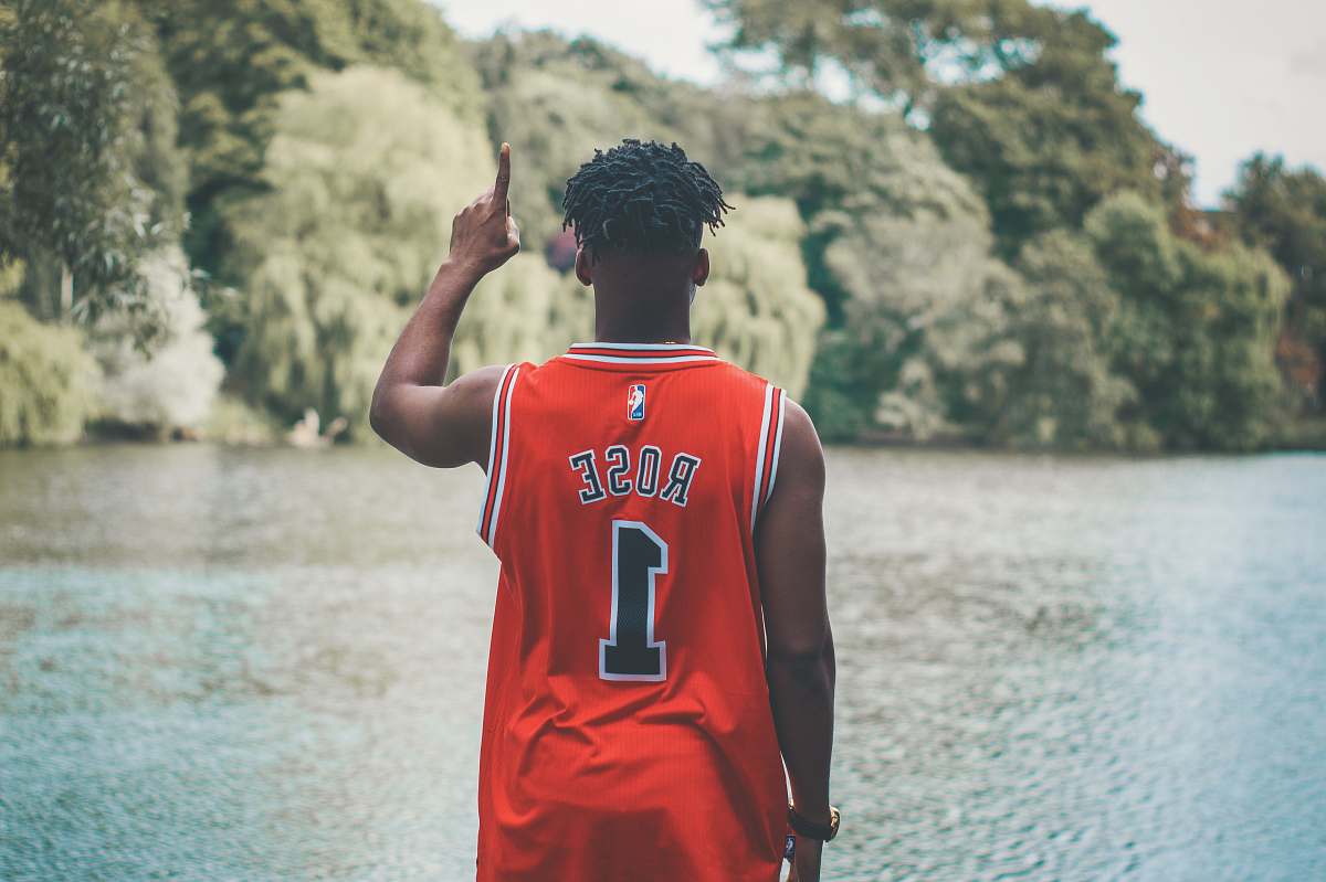 person man standing facing body of water while raising his right arm people