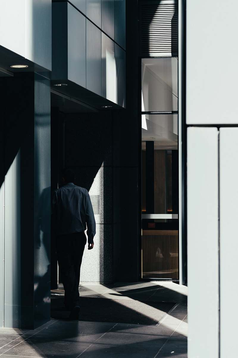 person man walking on gray tiled pathway inside building people