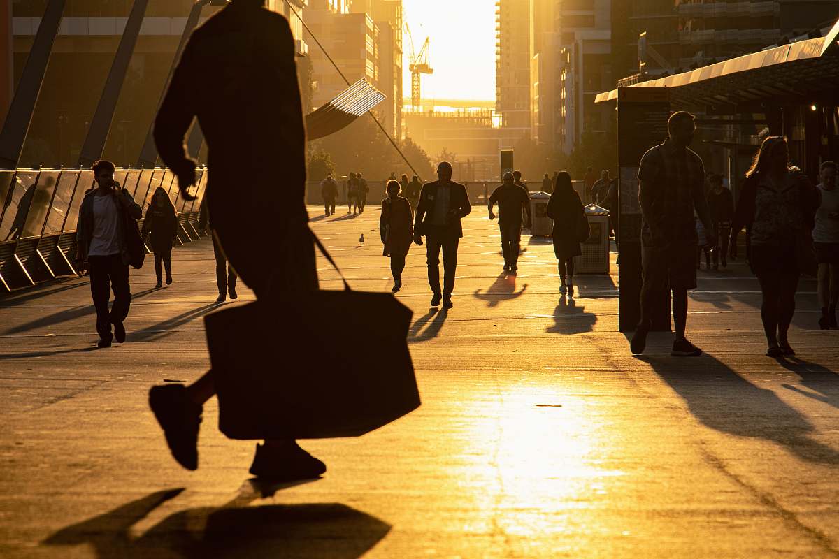 person man walking on the field carrying bag path