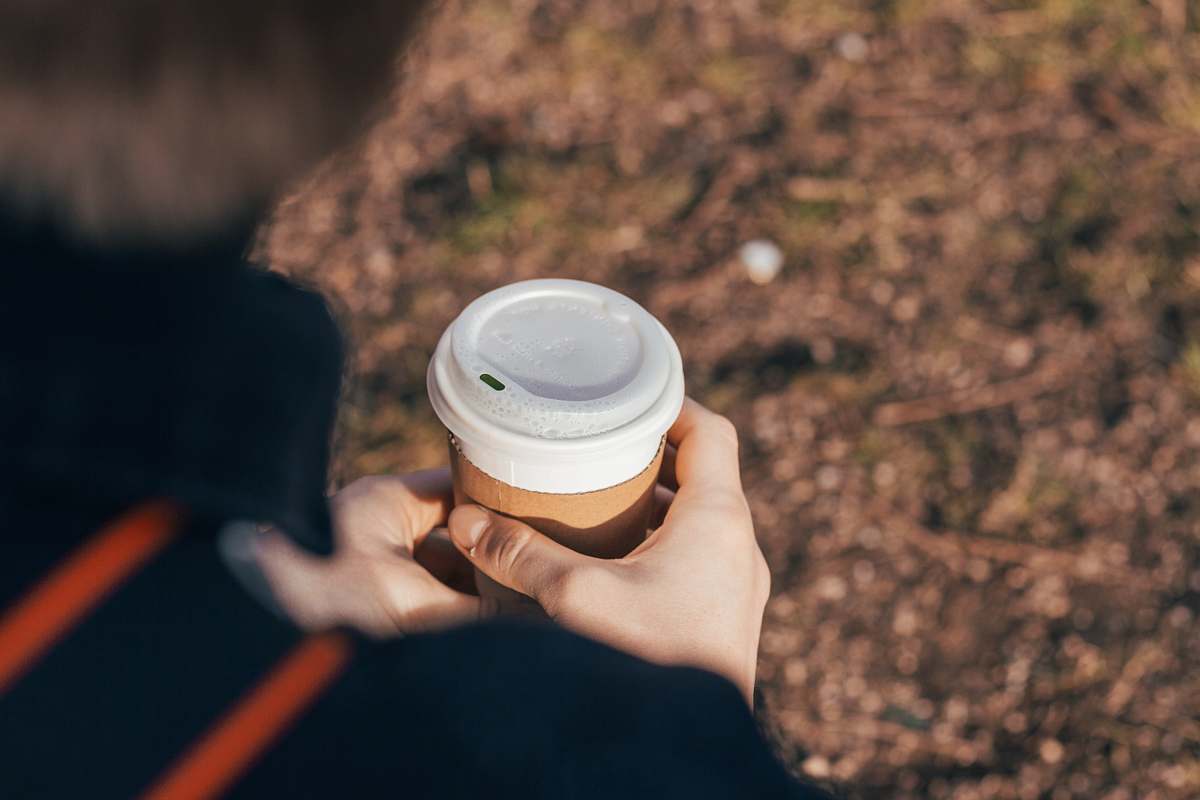 person person holding white and brown cup finger