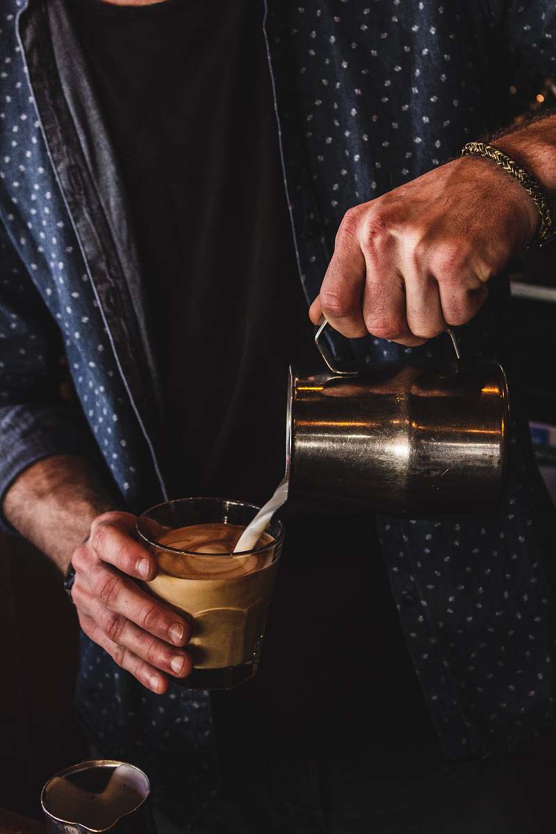person person pouring milk on coffee finger
