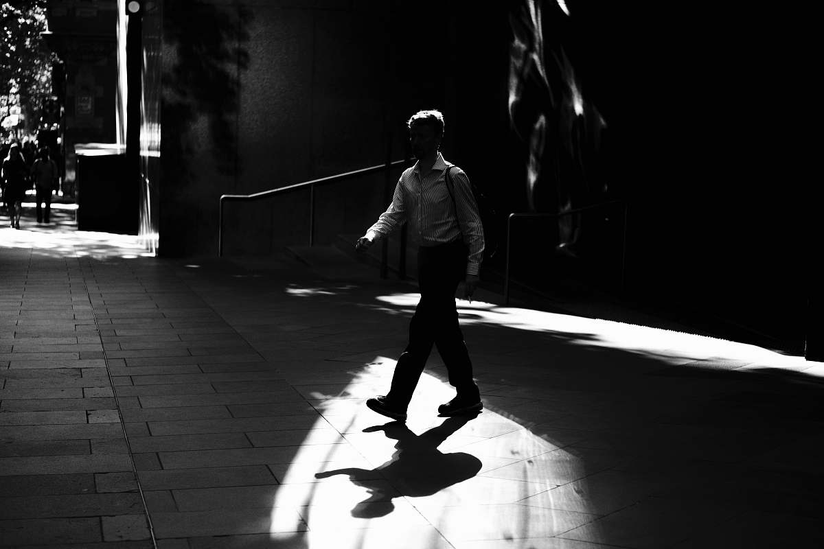 person person walking on concrete pavement black-and-white