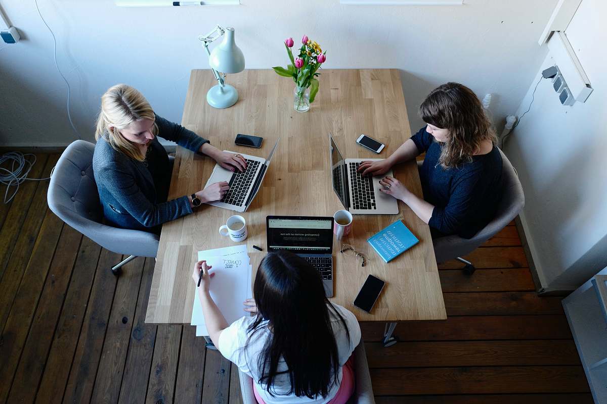 furniture three women sitting around table using laptops table