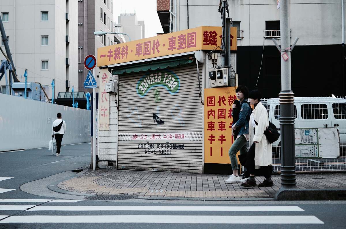 person two women walking near street post and pedestrian lane people