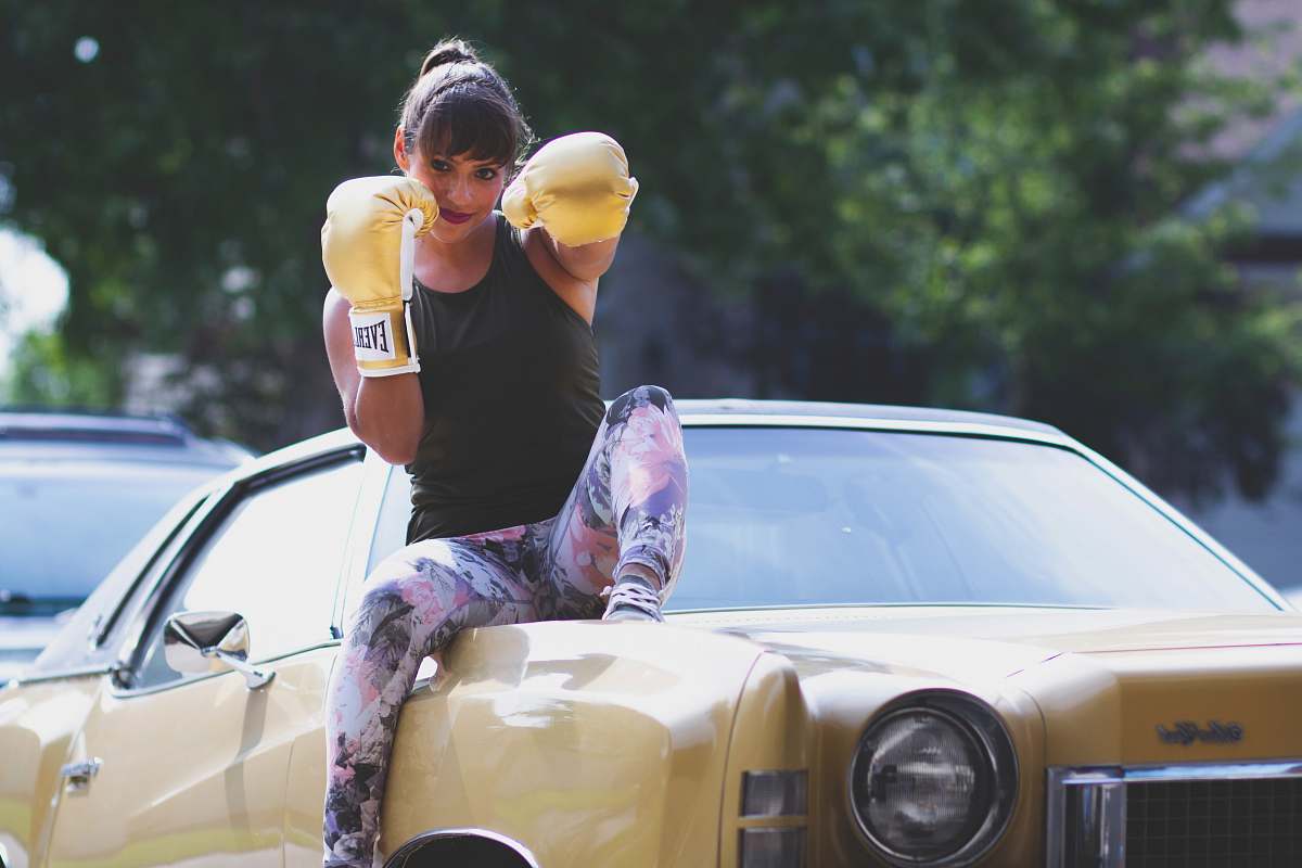 person woman sitting on yellow car while punching air people