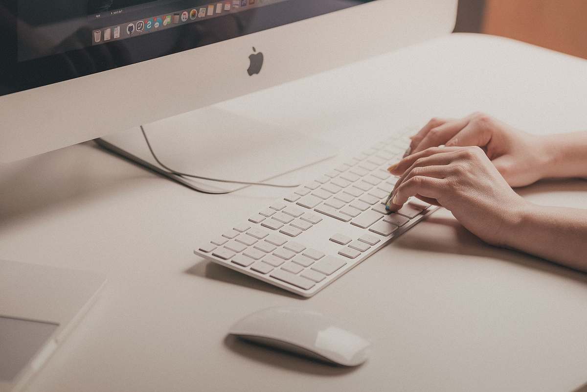 work person typing on Apple keyboard hands