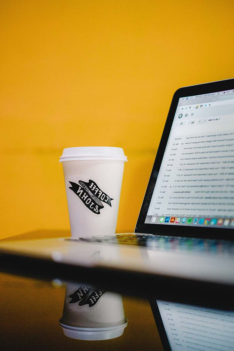 cup coffee & john-printed cup with lid beside MacBook computer