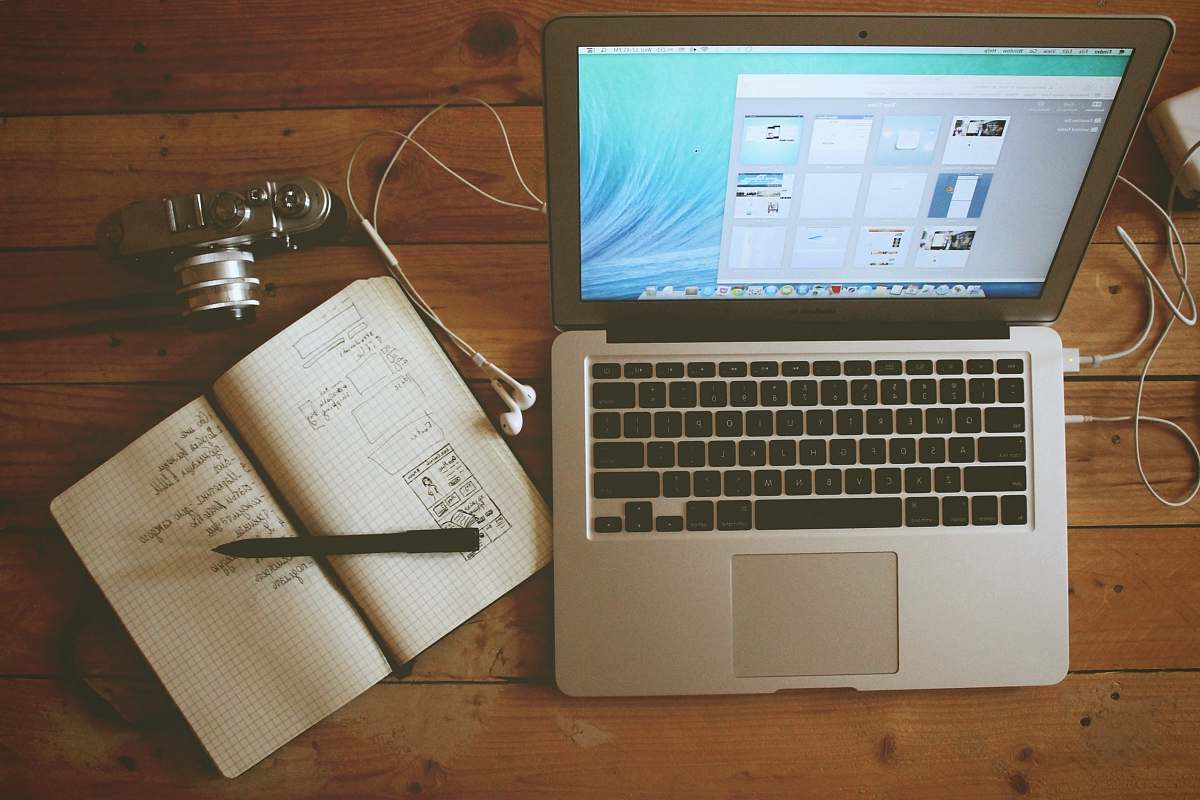computer turned on MacBook Air beside white notebook wood