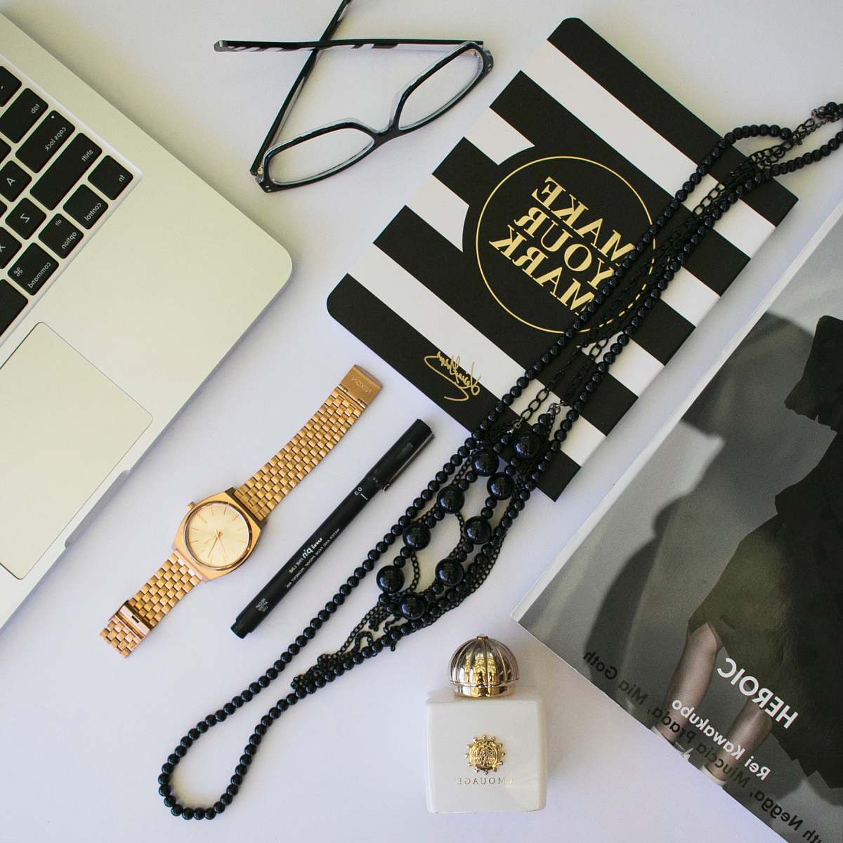 australia clear eyeglasses with black frames; beaded black necklaces; black pen; round gold-colored analog watch with link bracelet in flat lay photography flat lay
