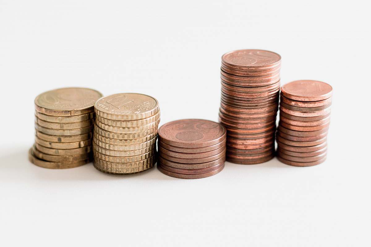 finance stacked round gold-colored coins on white surface coin