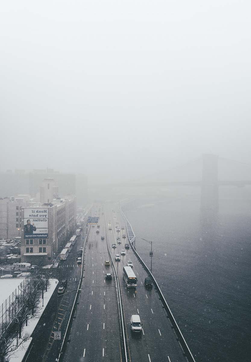 grey aerial view of vehicle on road beside body of water fog