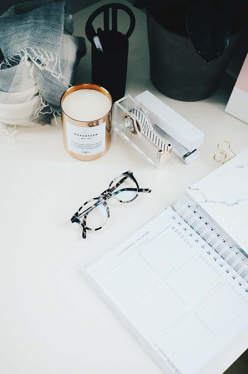 desk black framed eyeglasses beside spiral notebook work