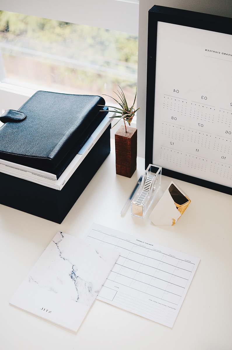 desk books and calendar on white table plant