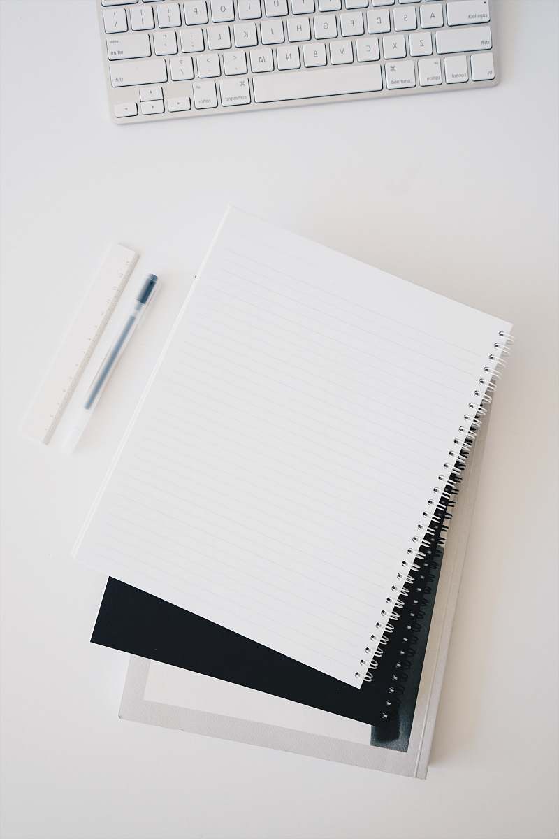 grey empty spiral notebook near keyboard and pen desk