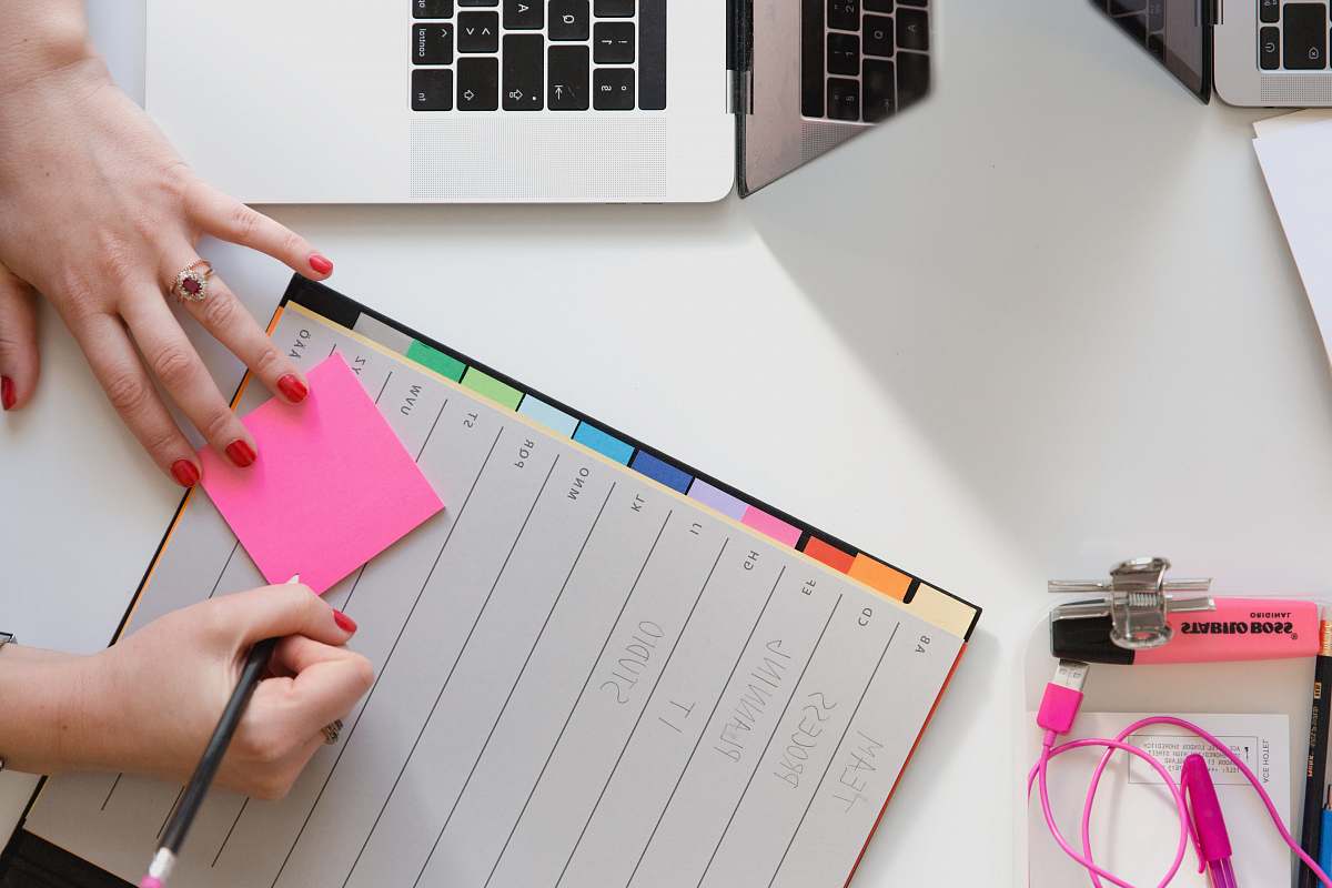 desk person holding pencil and stick note beside table work