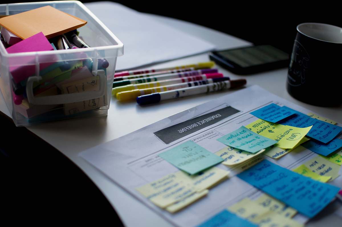 cup sticky notes on paper document beside pens and box desk