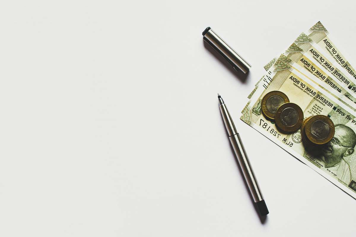 financing gray pen beside coins on Indian rupee banknotes invest