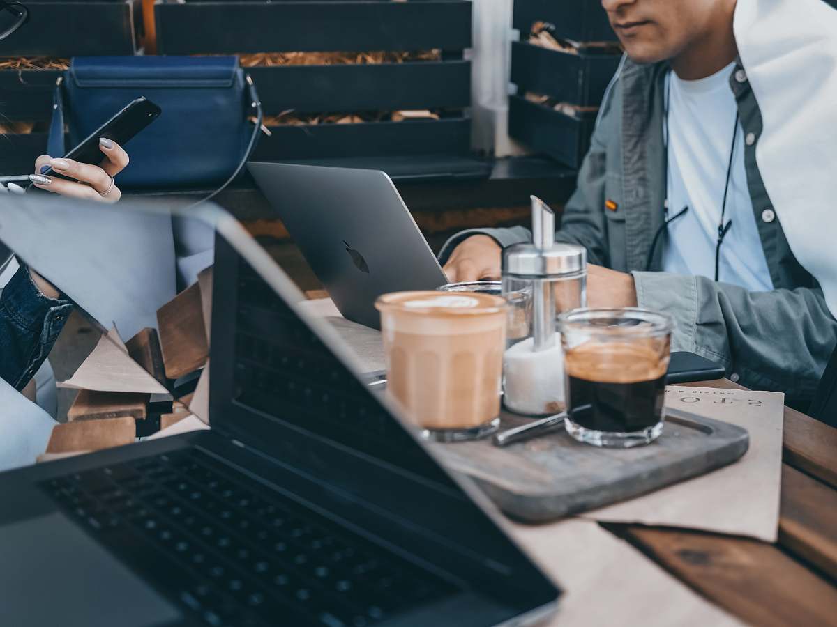 This vibrant image captures two professionals deeply engaged in their work, each utilizing a MacBook at a stylish table. The scene exemplifies the spirit of collaboration and productivity in a contemporary office environment. Perfect for articles about remote work, digital collaboration, or the modern workspace, this image highlights the synergy of technology and teamwork.