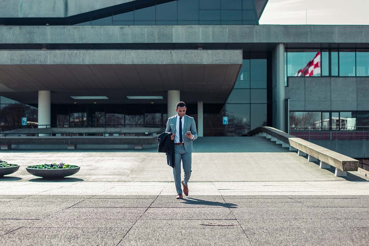 human man walking while holding black coat suit