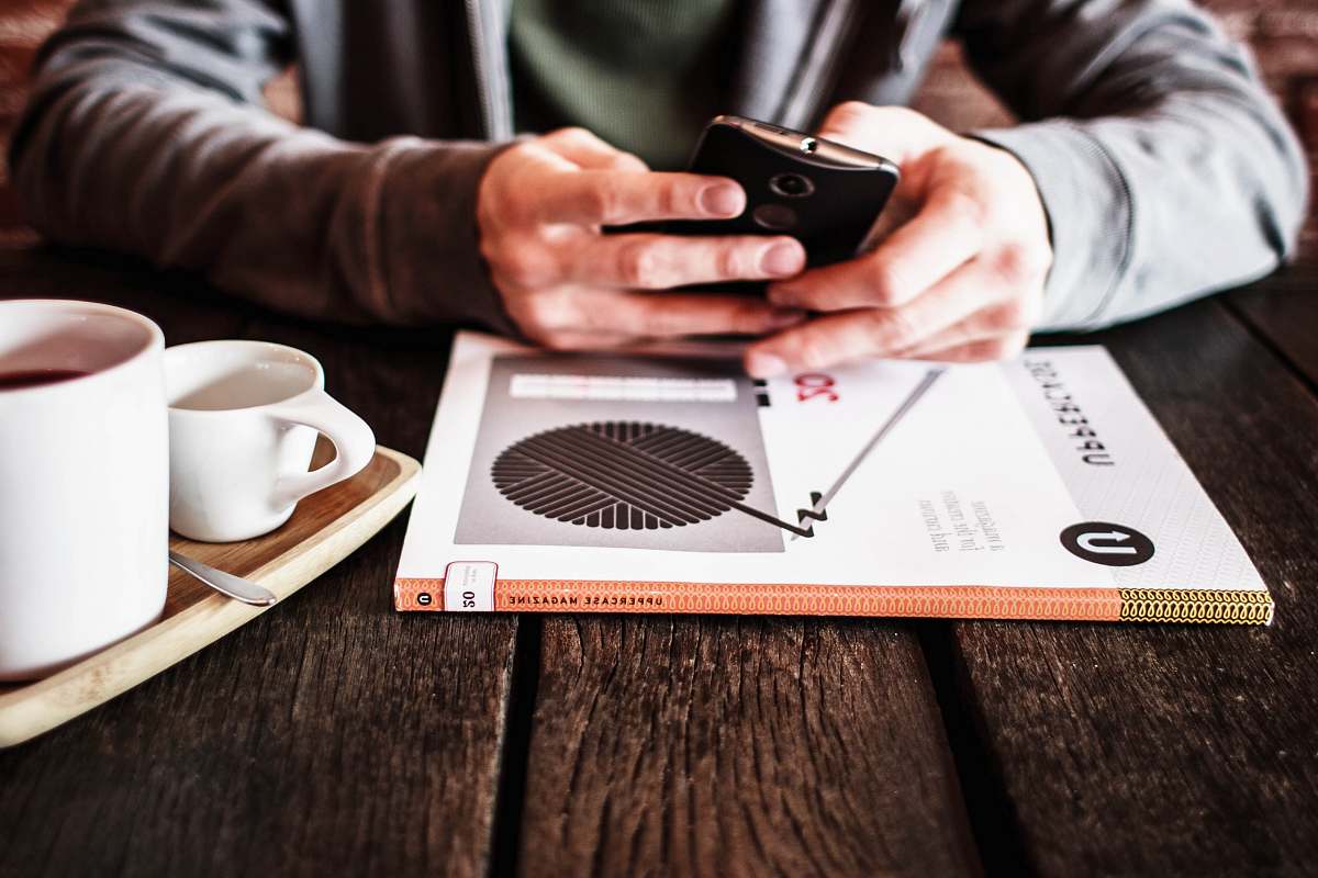 person person holding black Android smartphone while leaning on table human
