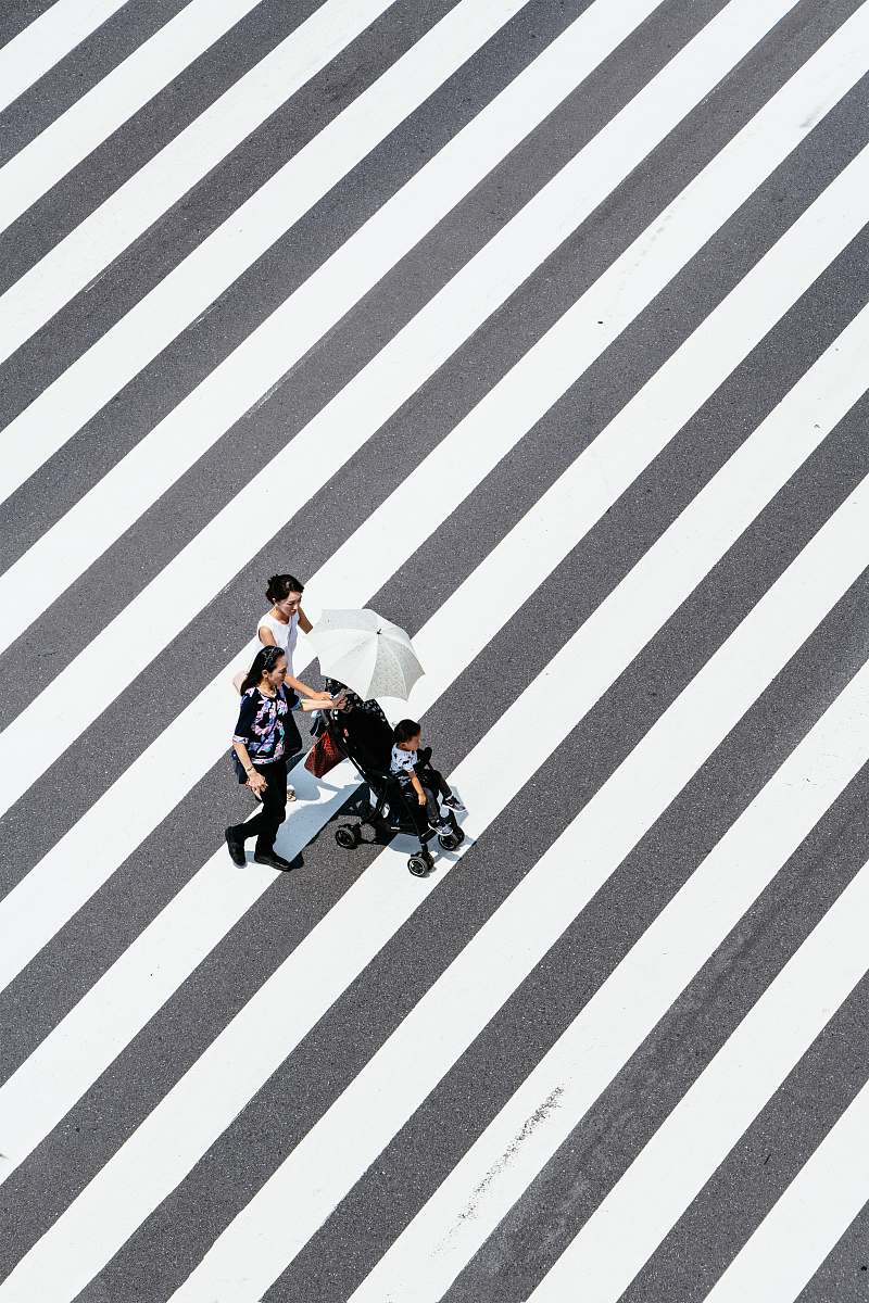 tarmac two women and baby crossing striped floor road