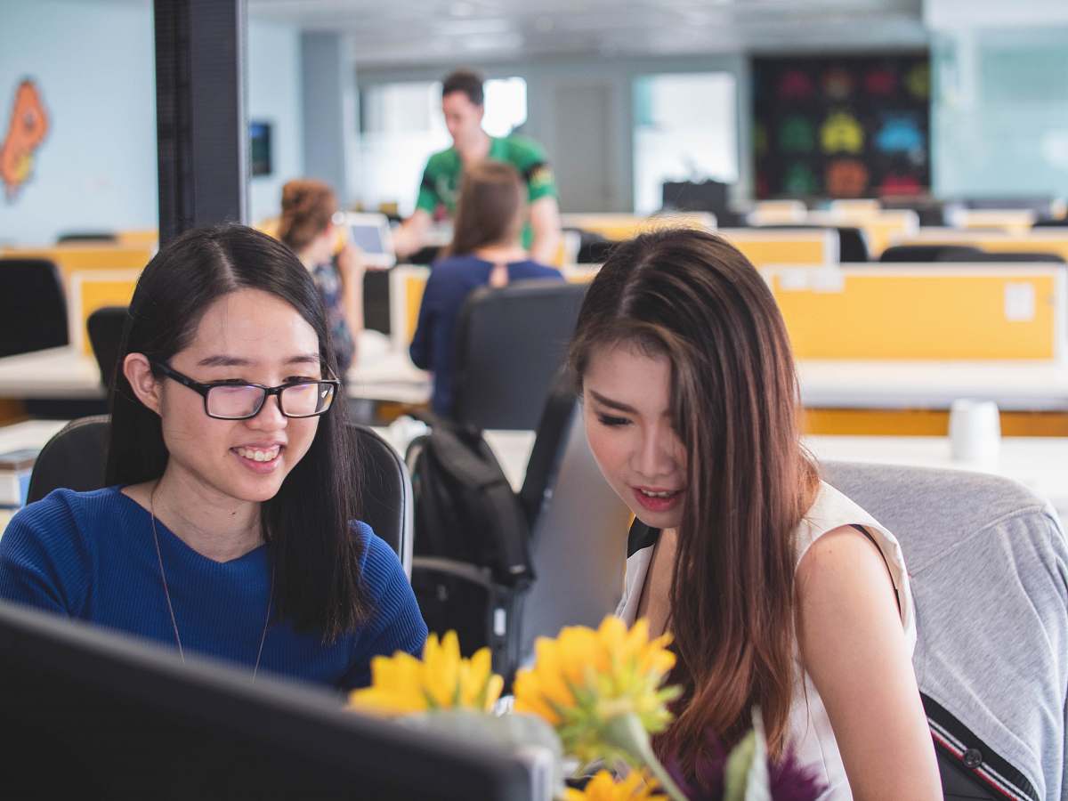 person two women smiling in front of computer monitor human