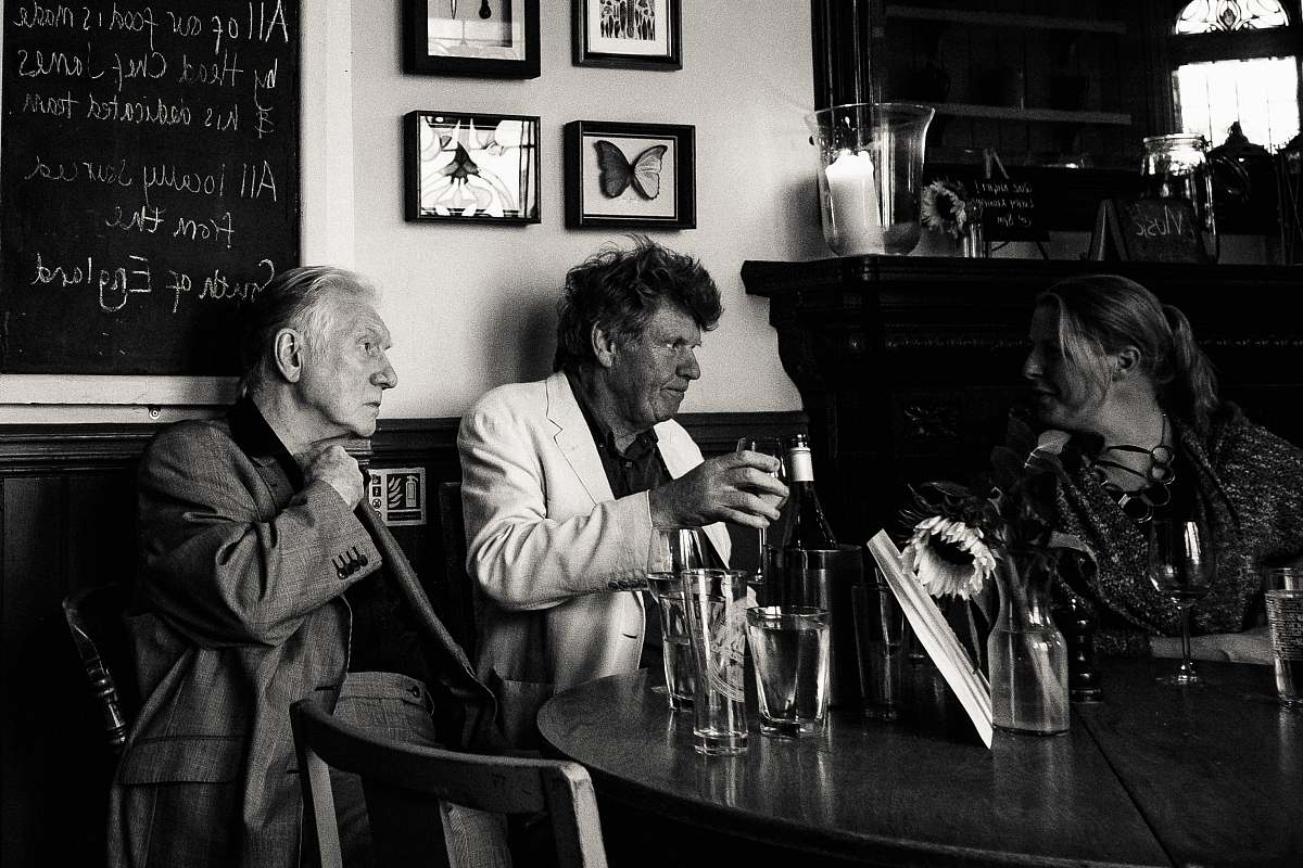 people grayscale photo of three man sitting beside table human