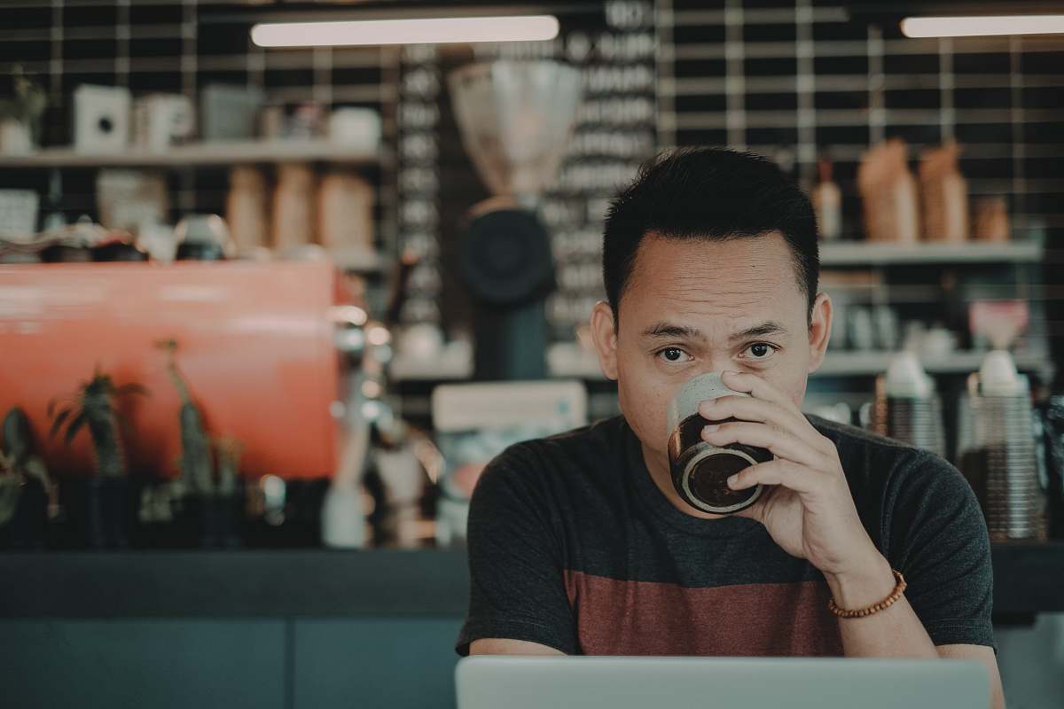 human man drinking on mug while sitting people