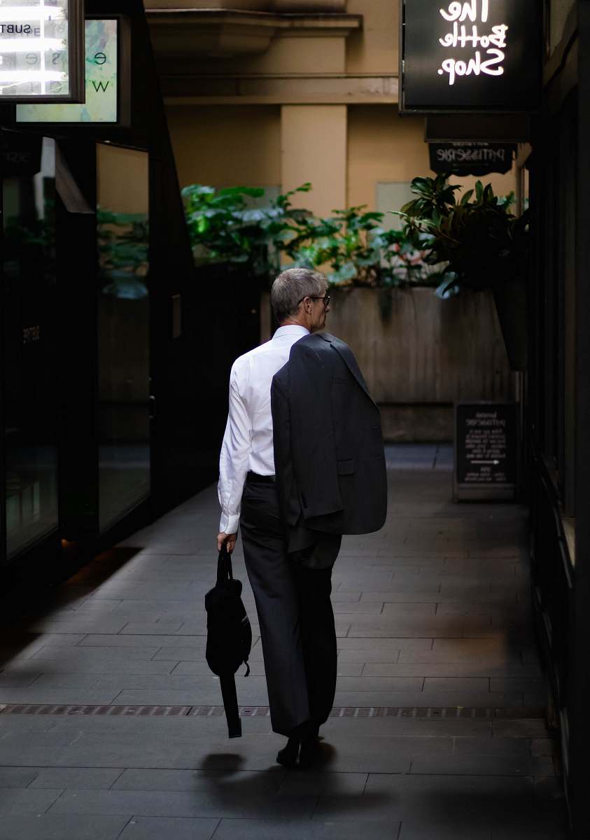 people man holding black bag walking on road jar