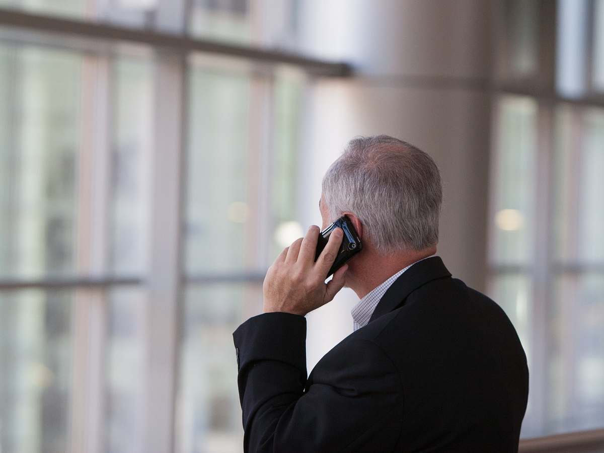 people man holding black smartphone in front of a windowpane human