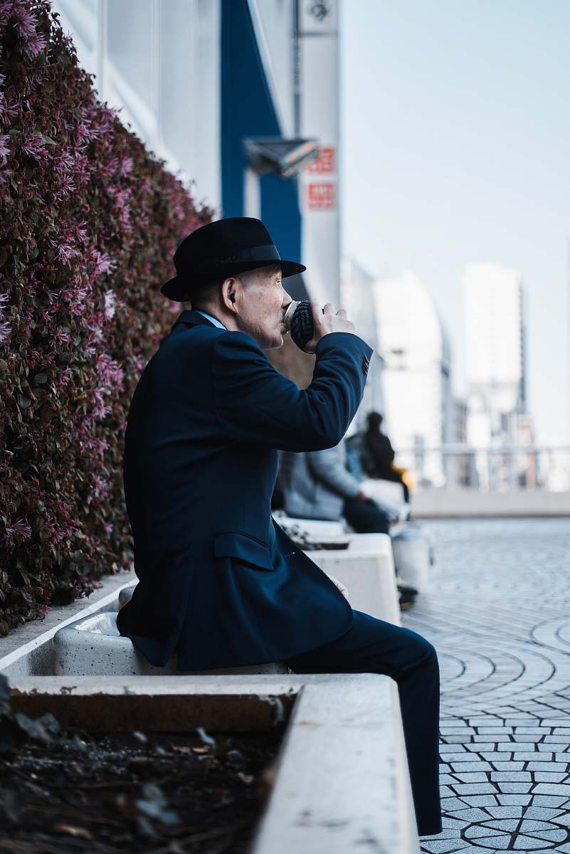 human man sitting on chair beside floral wall people