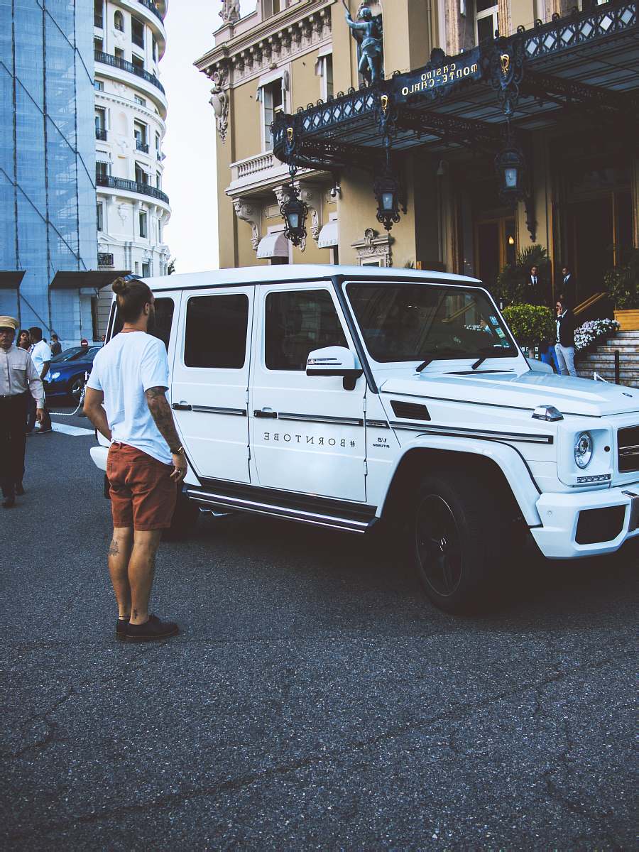 human man standing beside white SUV during daytime car