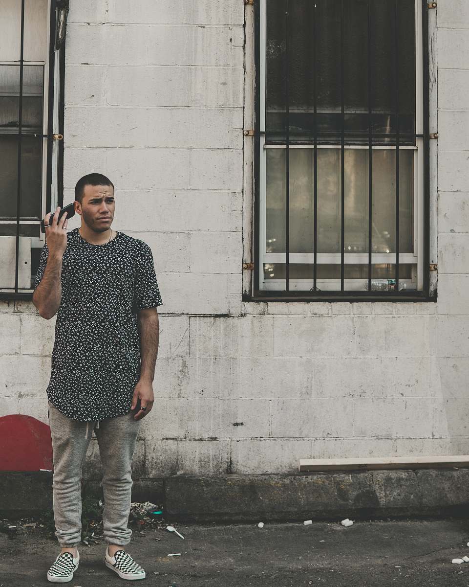 human man standing in front of building while holding phone during daytime people
