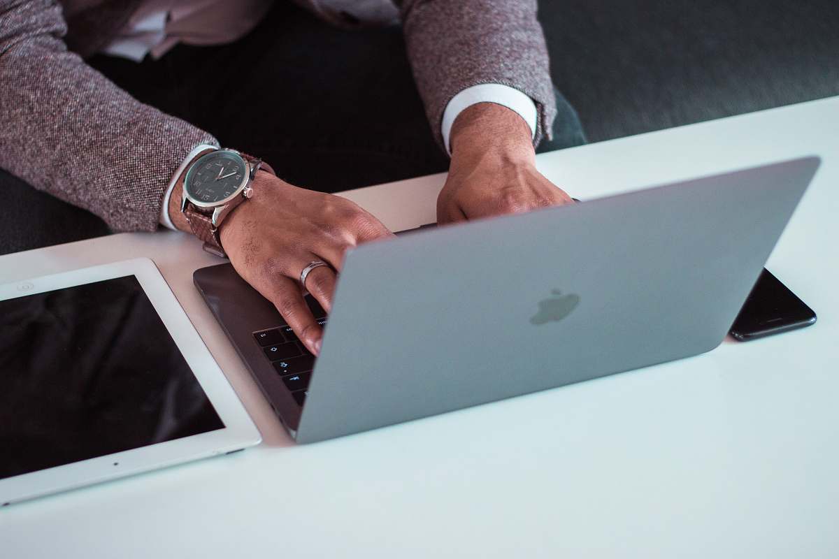 electronics man using MacBook between iPad and iPhone wristwatch