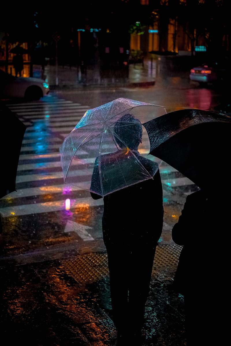 human man wearing black suit jacket holding clear umbrella in front of pedestrian lane people