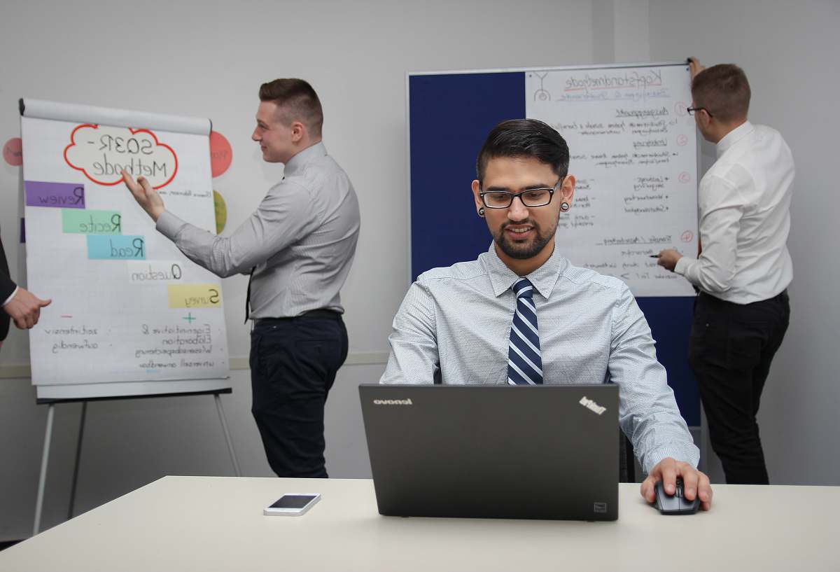 human man wearing white dress shirt sitting on chair while using gray Dell ThinkPad laptop computer