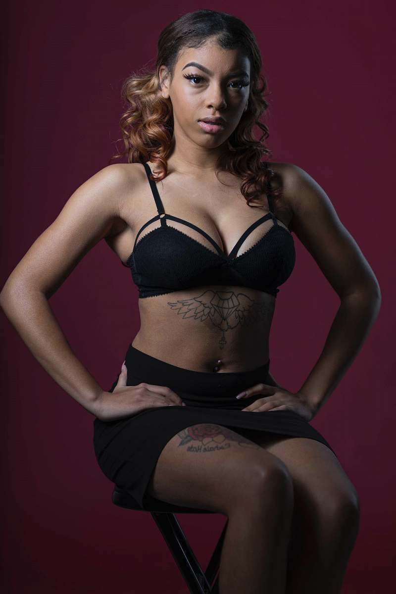 apparel woman in black brassiere sitting on stool clothing
