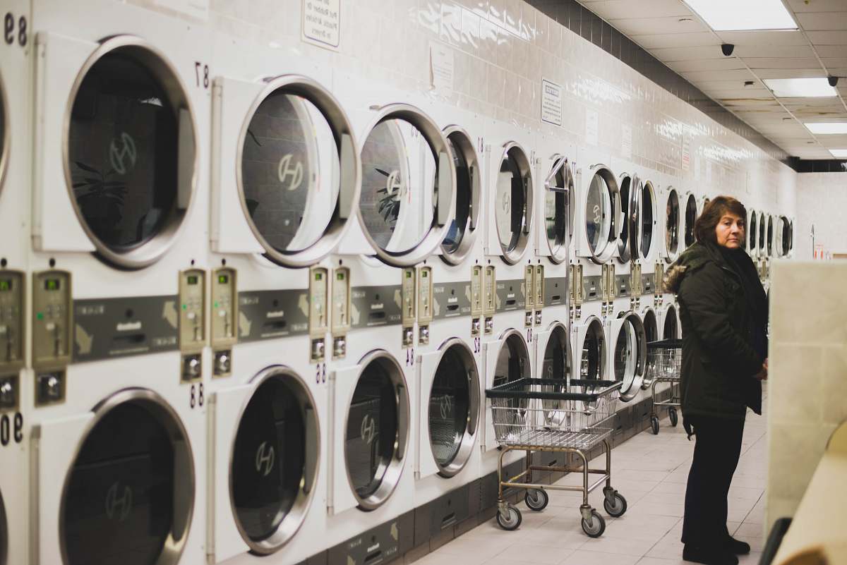 human woman in black jacket near washers laundry