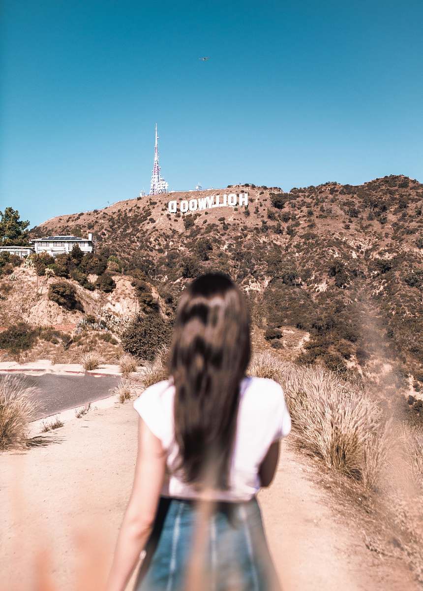 human woman in white top standing beside road ground