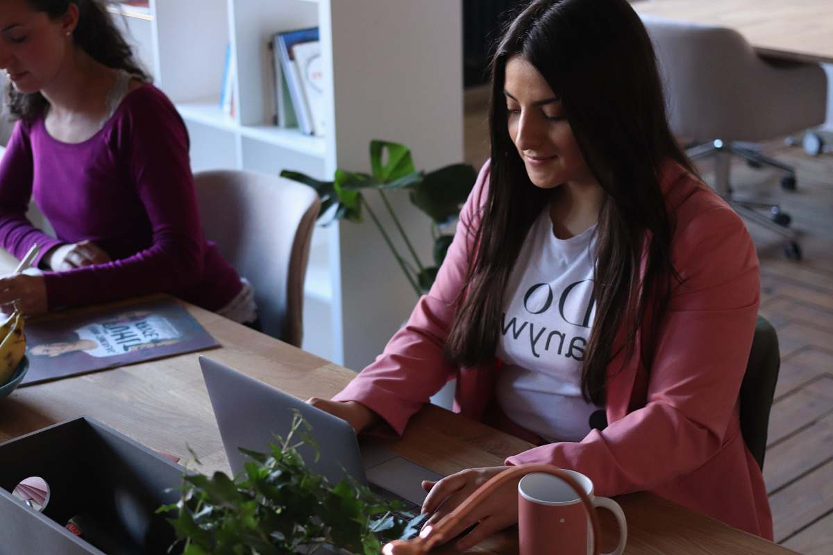 human woman sitting facing on laptop coffee cup