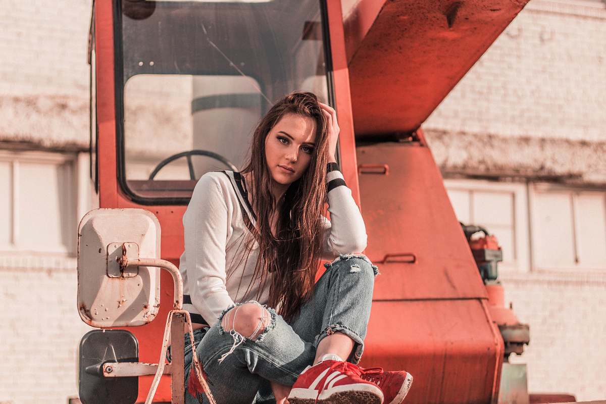 people woman sitting in front of red heavy equipment while resting her hand on head human
