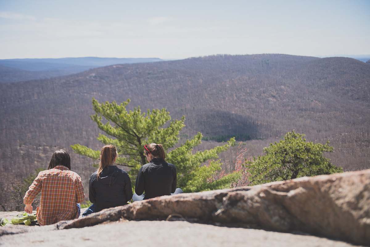 human women sits on ground near green trees people