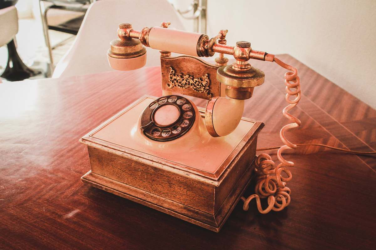 electronics white and brown rotary telephone on brown wooden table dial telephone