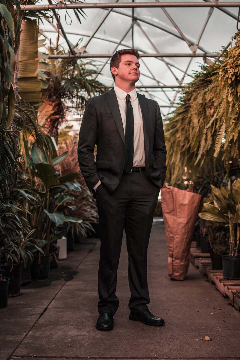 suit man wearing suit jacket standing between the plants human