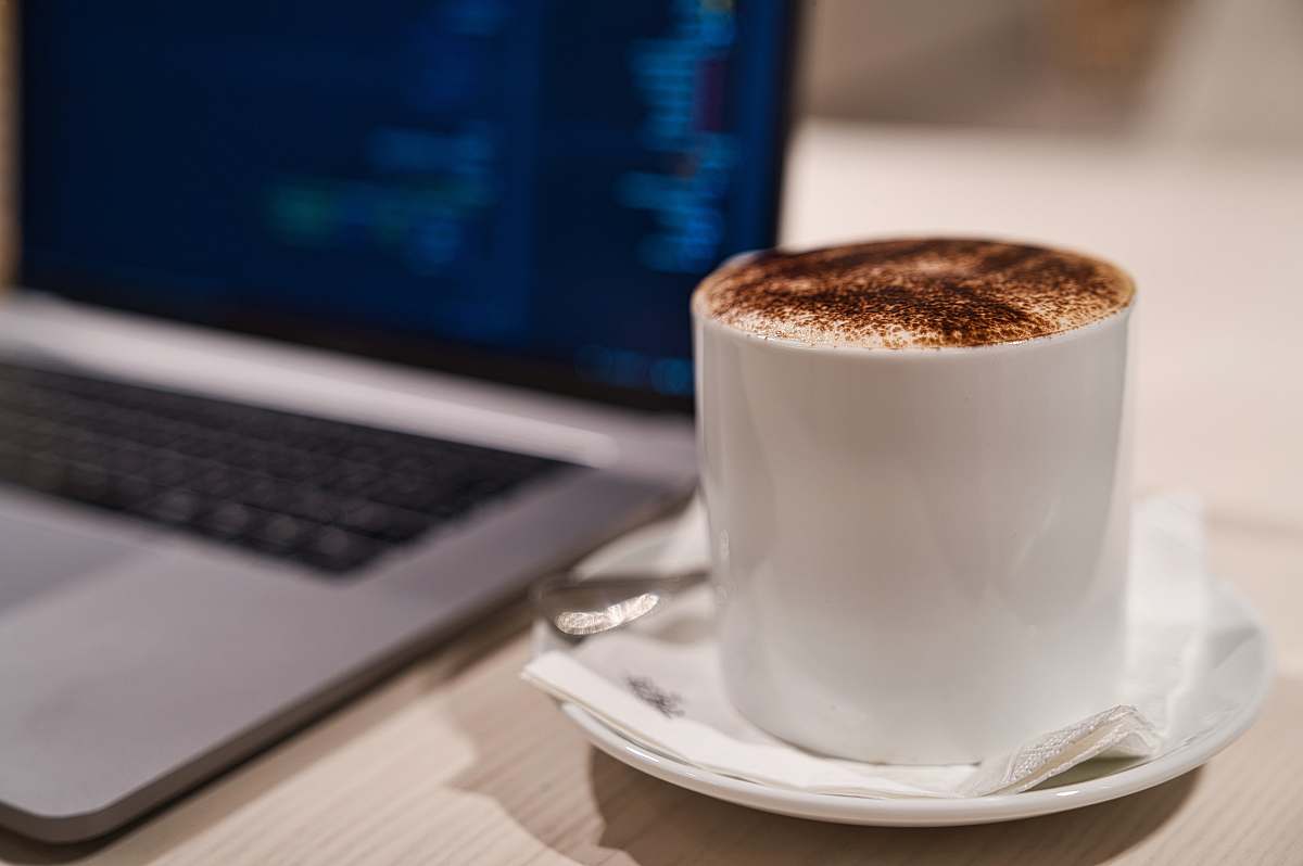 saucer cappuccino in cup on saucer beside laptop laptop