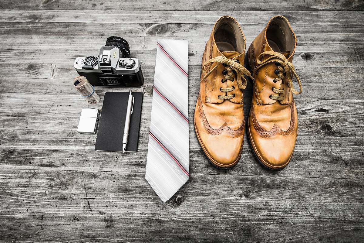 shoes pair of brown leather boots beside necktie next to pen, notebook, and MILC camera footwear