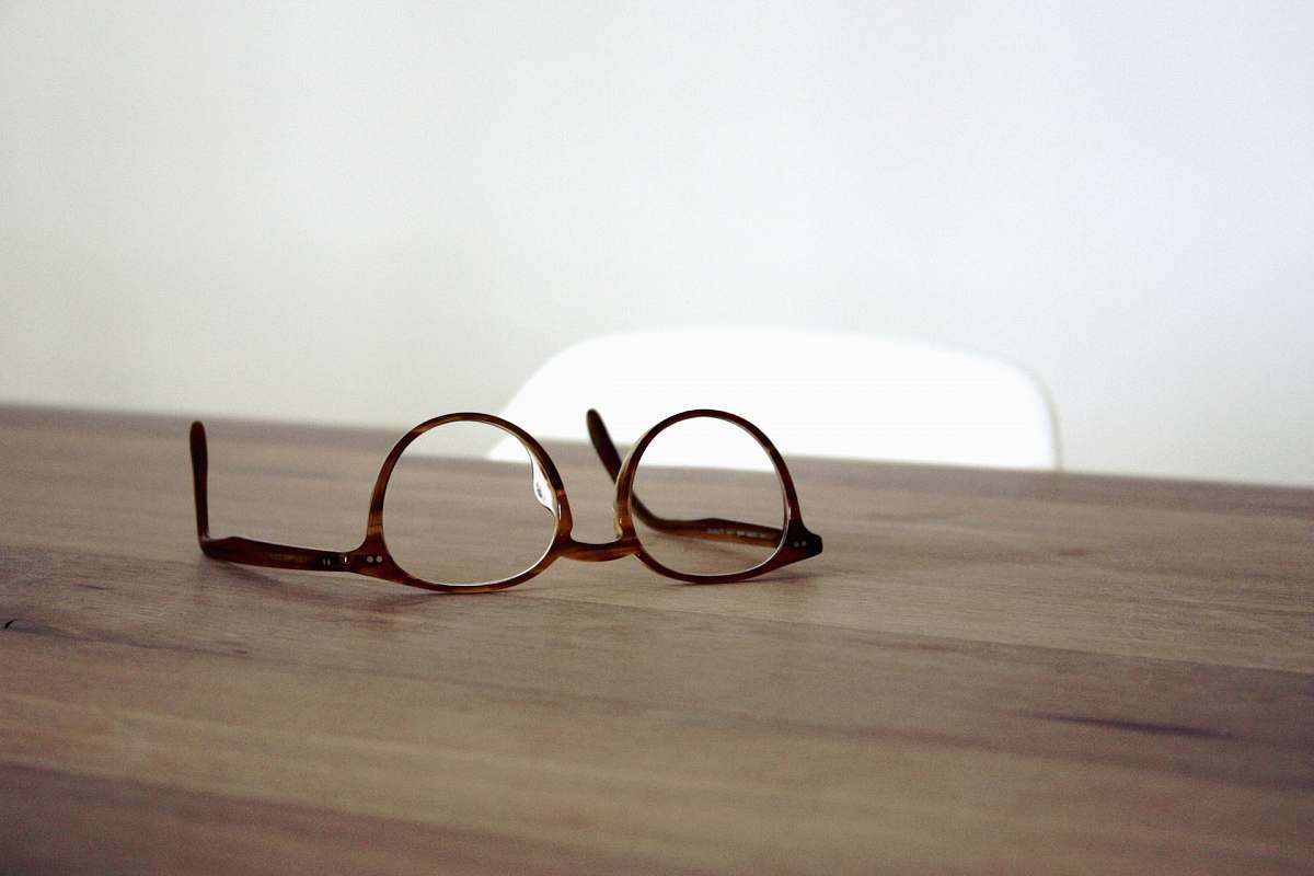 glasses eyeglasses with brown frames on brown wooden surface minimal