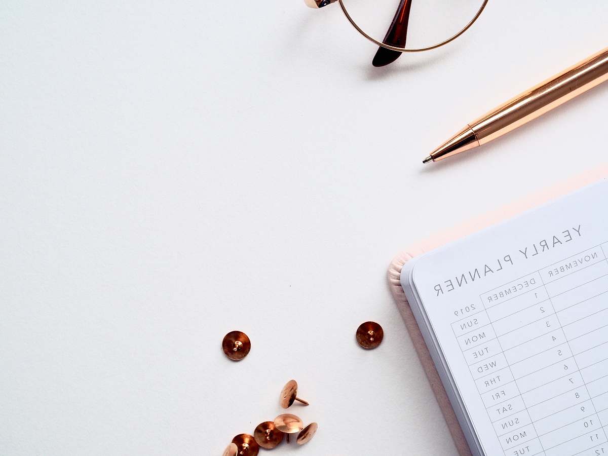 electronics buttons and thumbtacks beside planner book on table phone