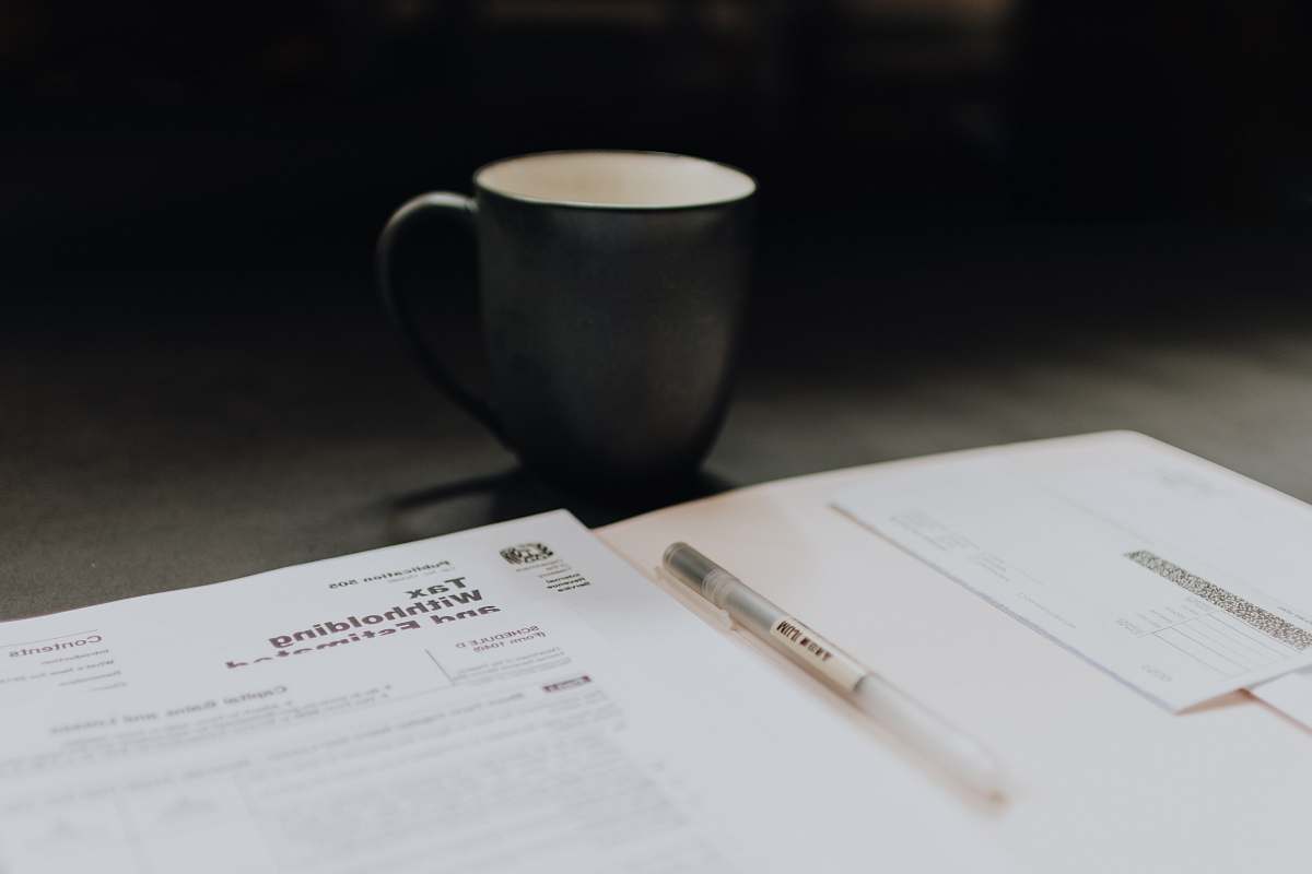 pen coffee mug near open folder with tax withholding paper diary