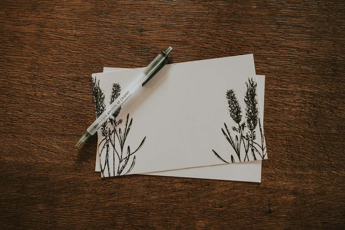paper white pen on top of two white and black floral stationeries pen